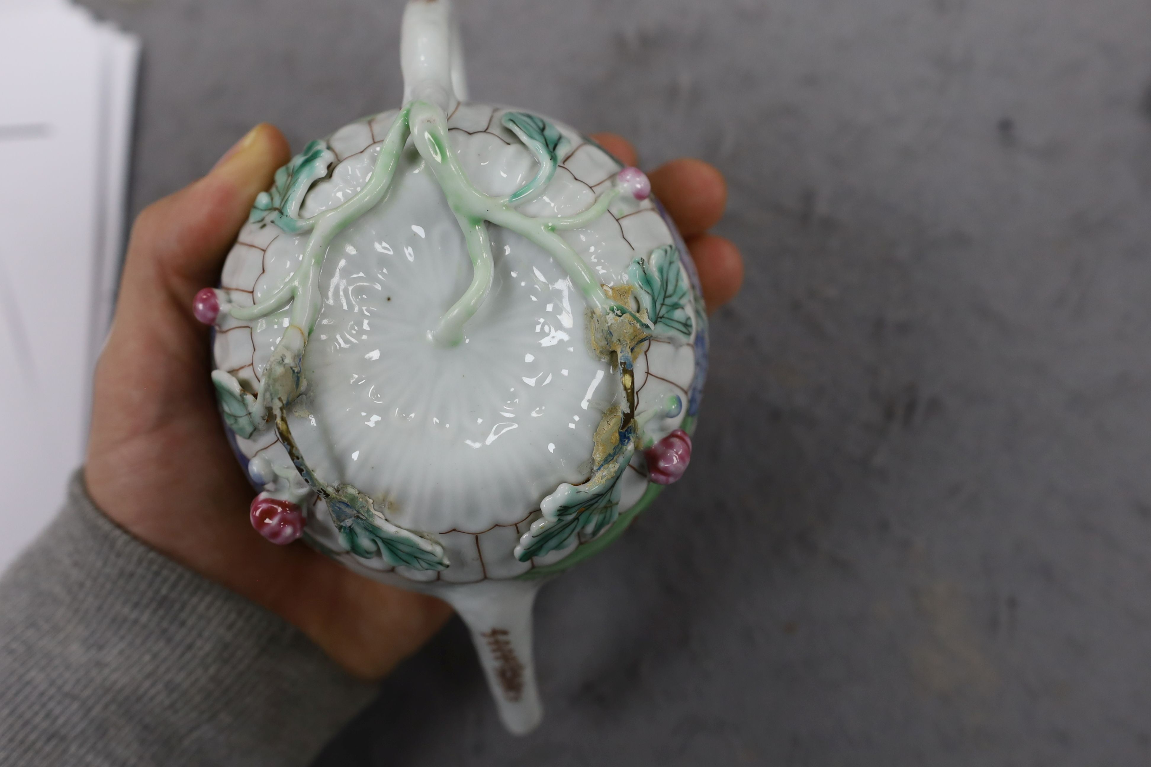 A Chinese famille rose chrysanthemum moulded teapot, early Qianlong period, painted with a cockerel amongst flowers, on a cage work base, 10 cms high
